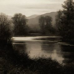 a black and white photo of a lake surrounded by trees