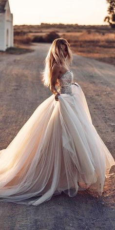 a woman in a wedding dress is standing on the road with her back to the camera