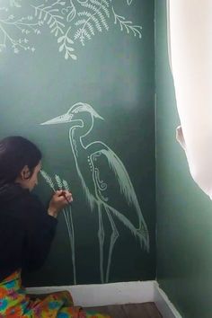 a woman is drawing on the wall with chalk