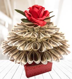 a red rose sitting on top of a pile of dollar bill origami flowers