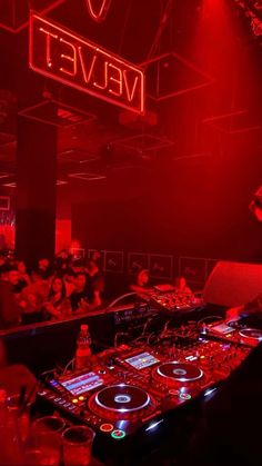 a dj mixing in front of a red light at a party with people sitting around