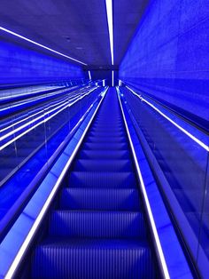 an escalator in a subway station with blue lighting