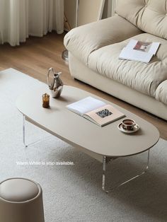 a white coffee table sitting on top of a wooden floor next to a beige couch