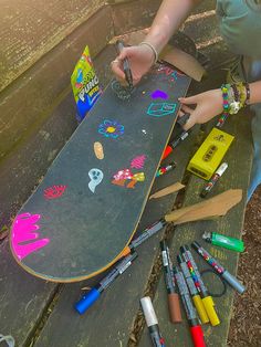 a skateboard that is sitting on the ground with crayons and markers around it