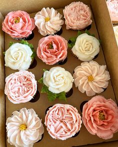 cupcakes in a box with pink and white frosting flowers on the top