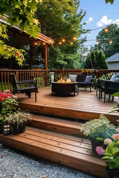 Wooden deck with string lights, cozy seating around a fire pit, and lush green surroundings featuring various colorful plants and flowers. Backyard Deck Aesthetic, Fire Pits On Wooden Decks, Covered Patio And Deck Combo, Tiny Home Deck Ideas, Basic Deck Ideas, Creative Deck Design, Cozy Deck Ideas Outdoor, Back Deck Furniture Ideas, Deck Oasis Ideas