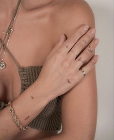 a woman with tattoos on her arm and wrist is holding her hands in front of her chest