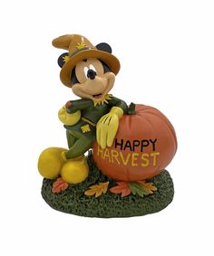 a mickey mouse figurine holding a pumpkin with the words happy harvest written on it