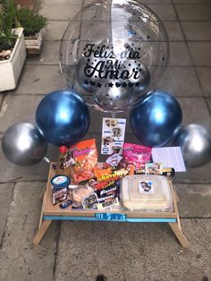 a table topped with balloons and other items on top of a cement floor next to a sidewalk