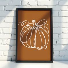 a white pumpkin on a brown background in front of a brick wall with a black frame