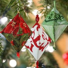 three origami ornaments hanging from a christmas tree