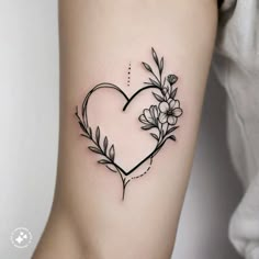 a heart shaped tattoo with flowers and leaves on the back of the arm, in black ink