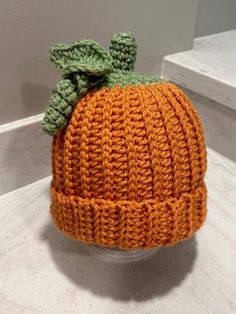 an orange knitted hat sitting on top of a white counter next to a wall