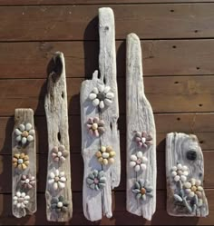 four wooden spoons with flowers painted on them are lined up against a wood wall