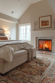 a bedroom with a bed, fireplace and rug in front of the bed is shown