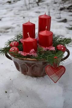 some red candles are in a bowl on the snow