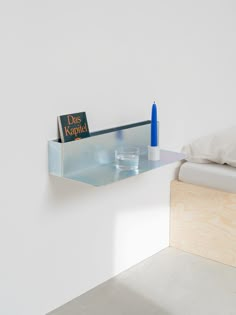 there is a book shelf on the wall next to a bed with a blue candle