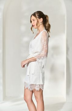 Made in a unique delicate white french lace design, the Lara Lace Robe is the perfect gift for the bride-to-be on her wedding day. Featuring scalloped lace edges along the neckline, hem and sleeve cuffs, this robe exudes old-world elegance. The body of the Lara Robe is fully lined to provide our brides the coverage they need. A slip dress is not required for under this robe, but if you're in search of one we recommend our White Bridal Slip Dress. Material: French lace with a fully lined bodySlee White Feminine Lace Top With Lace Trim, Long Sleeve Lace Wedding Dress With Lace Cuffs, Lace Wedding Dress With Lace Cuffs, White Long Sleeve Lace Dress With Lace Cuffs, White Feminine Lace Top, White Lace Bridesmaid Dress With Scalloped Lace, White Scalloped Lace Dress For Bridesmaid, White Long Sleeve Lace Dress With Lace Trim, White Lace Dress With Long Sleeves