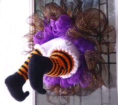 a purple and orange halloween wreath with a sock on it's front door hanger