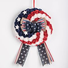 a patriotic wreath hanging from a red, white and blue ribbon