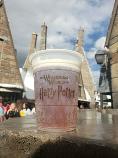 a plastic cup sitting on top of a wooden table in front of a castle like building