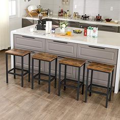 three stools sit at the center of a kitchen island with breakfast foods on it