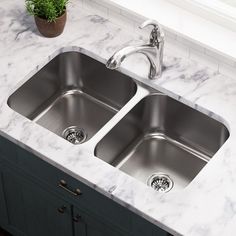 two stainless steel sinks in a kitchen with marble counter tops