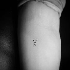 a black and white photo of a person's arm with a small tattoo on it