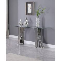 a glass table with two vases sitting on it's sides next to a gray wall