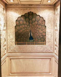 a peacock sitting on top of a wooden door in front of a wall mounted mirror