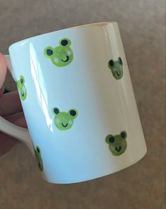 a hand holding a coffee mug with green bears on it