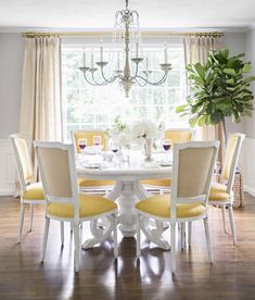 a dining room table with yellow chairs and a chandelier