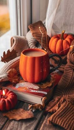 a cup of coffee sitting on top of a wooden table next to some pumpkins