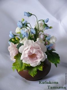 a vase filled with pink and white flowers on top of a white cloth covered table