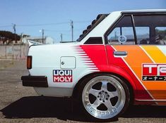 an orange, white and red car parked in a parking lot