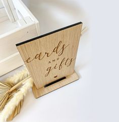 a wooden sign with the words sands and gifts written on it next to some feathers