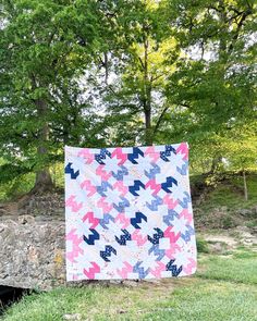 a pink and blue quilt sitting on top of a stone wall