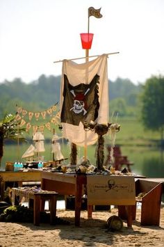 a pirate themed picnic table on the beach with an old flag hanging from it's side