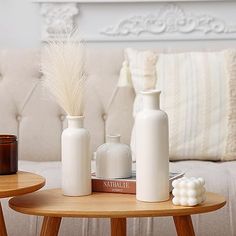 three white vases sitting on top of a wooden table next to each other in front of a couch