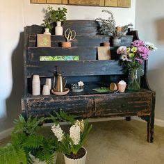 an old wooden bench with potted plants and flowers on the shelf next to it