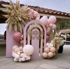 a pink and gold birthday party with balloons, palm trees, and an arch that says happy new year