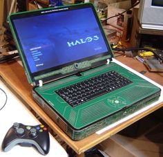 an open laptop computer sitting on top of a wooden desk next to a game controller