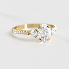 a yellow gold engagement ring with three diamonds on the band and an oval cut diamond in the center