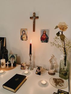 a table topped with pictures and candles next to a cross