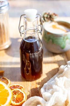 a bottle of syrup sitting on top of a cutting board next to sliced oranges