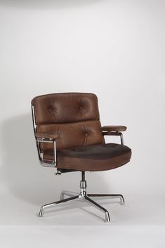 an office chair with brown leather upholstered on the back and chrome base, in front of a white wall