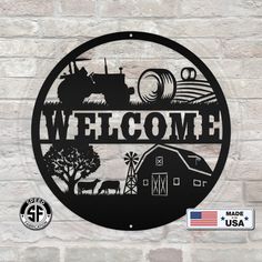 a metal sign that says welcome with farm scene and tractor in the background on a brick wall