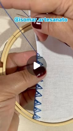 someone is doing something with their hands and using thread to sew on the hoop