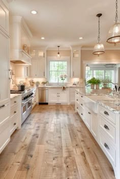 a large kitchen with white cabinets and wood floors