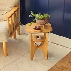 a small table with a potted plant on it next to a chair and wall